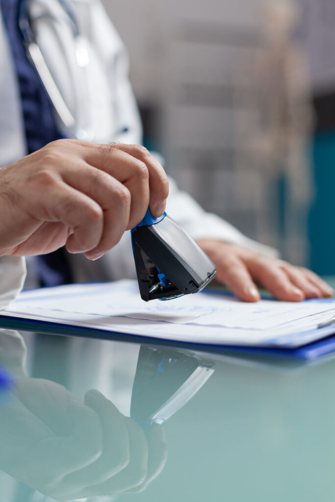 Doctor holding medical stamp to put on prescription paper